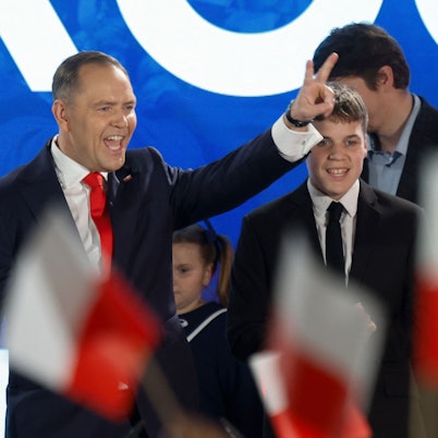Karol Nawrocki, candidate for the 2025 Polish presidential election supported by Poland's right-wing Law and Justice (PiS) party, flashes the victory sign in front of supporters as exit polls were announced on tv during their election night event at the Mala Warszawa Theatre in Warsaw, Poland, during the second round of the presidential elections on June 1, 2025. The centrist and nationalist candidates in Poland's presidential election on June 1 both claimed victory after an exit poll indicated they were neck and neck. (Photo by Wojtek RADWANSKI / AFP)