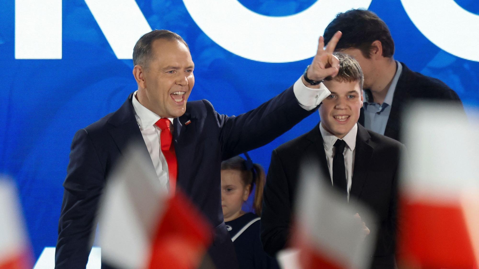 Karol Nawrocki, candidate for the 2025 Polish presidential election supported by Poland's right-wing Law and Justice (PiS) party, flashes the victory sign in front of supporters as exit polls were announced on tv during their election night event at the Mala Warszawa Theatre in Warsaw, Poland, during the second round of the presidential elections on June 1, 2025. The centrist and nationalist candidates in Poland's presidential election on June 1 both claimed victory after an exit poll indicated they were neck and neck. (Photo by Wojtek RADWANSKI / AFP)