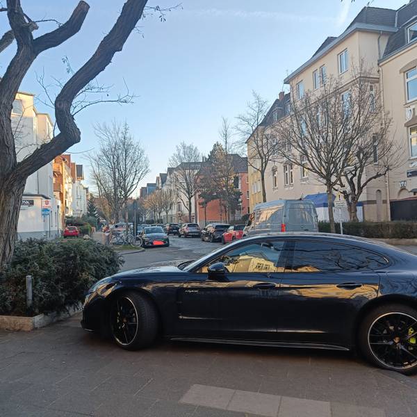 Ein Auto steht auf einem Gehweg, so dass Fußgänger die Straße nicht überqueren können.