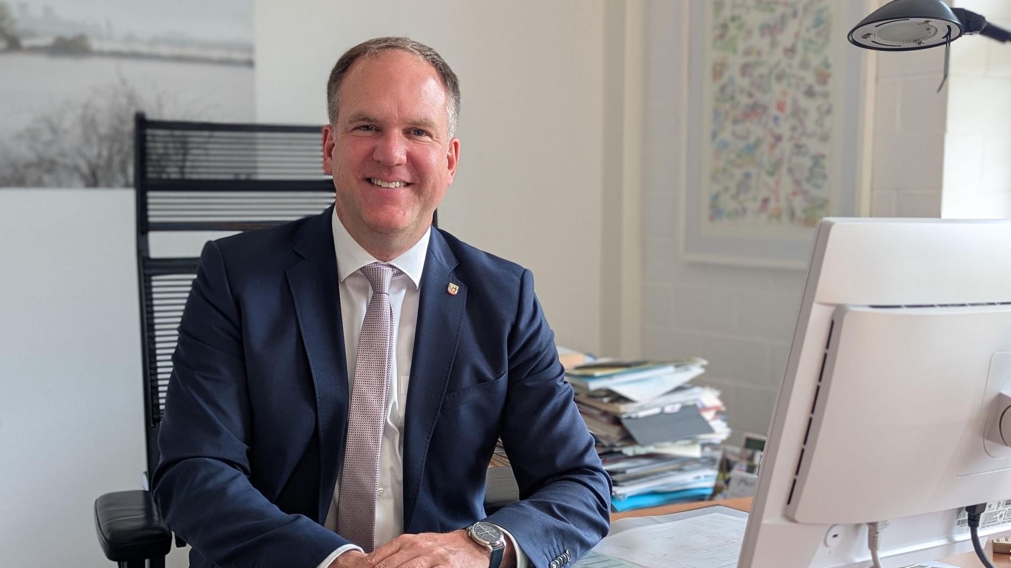 Das Foto zeigt Bürgermeister Dirk Breuer hinter einem Computerbildschirm an seinem Schreibtisch.