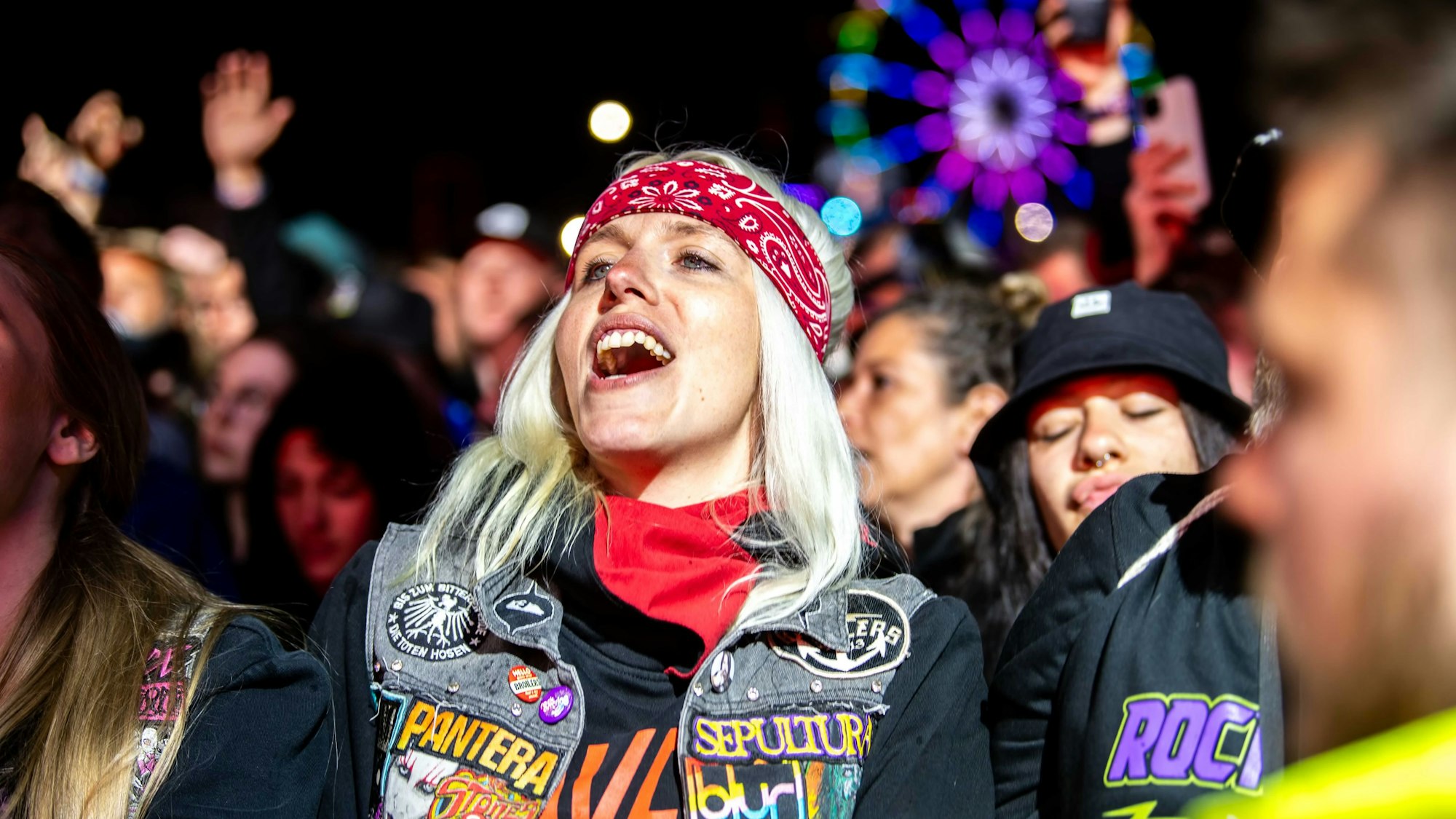 Das Bild zeigt eine Frau, die vor der Bühne steht und zu einem Song der Broilers mitsingt.