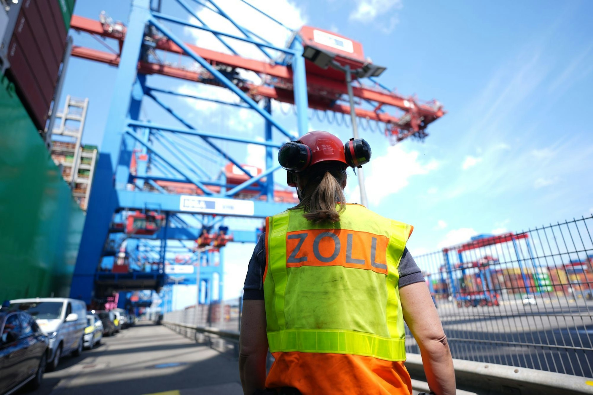 Eine Zollbeamtin steht neben einem Containerschiff im Hamburger Hafen.