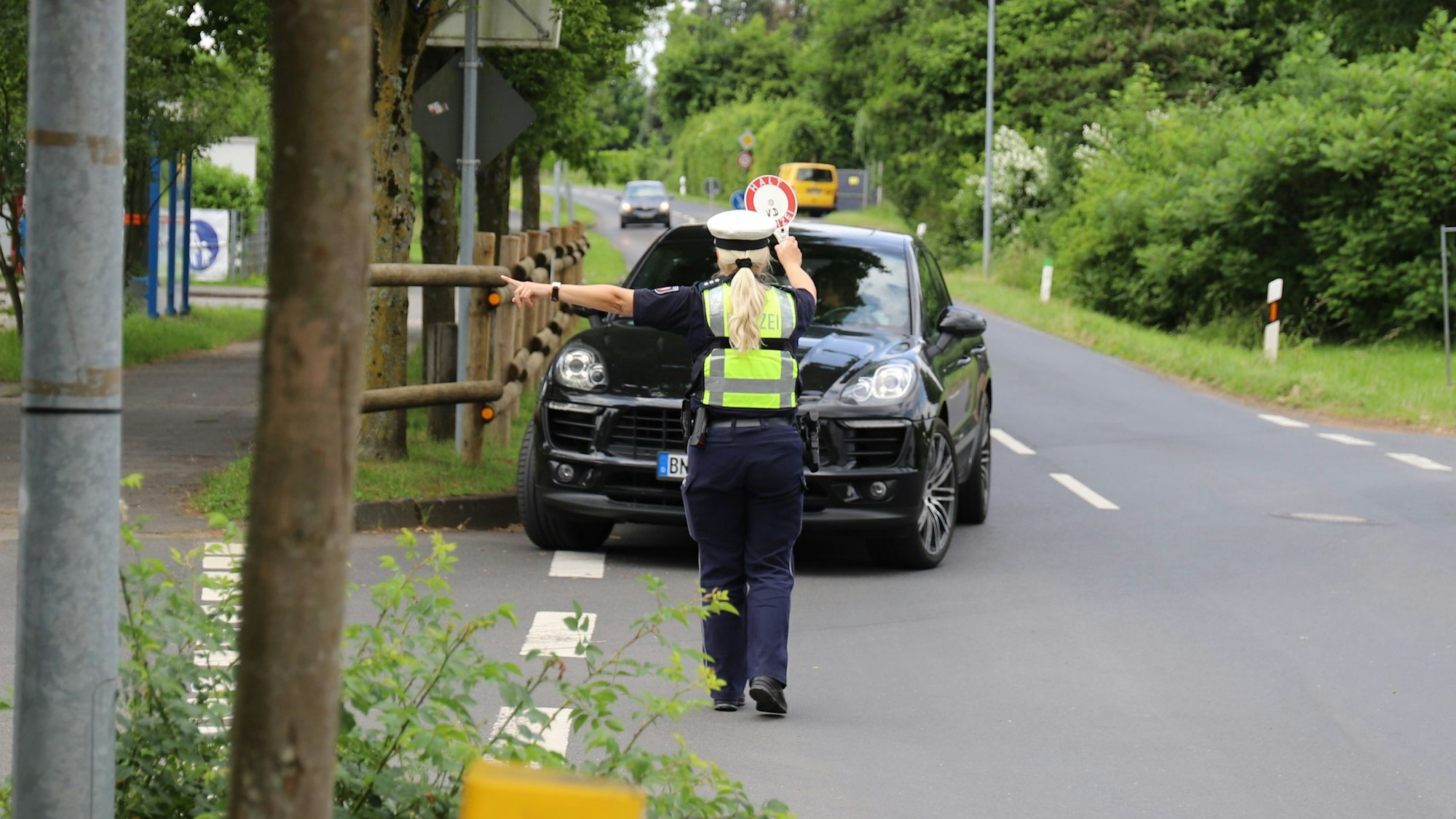 Eine Polizistin winkt einen Autofahrer auf einen Parkplatz heraus, der zu schnell unterwegs war.