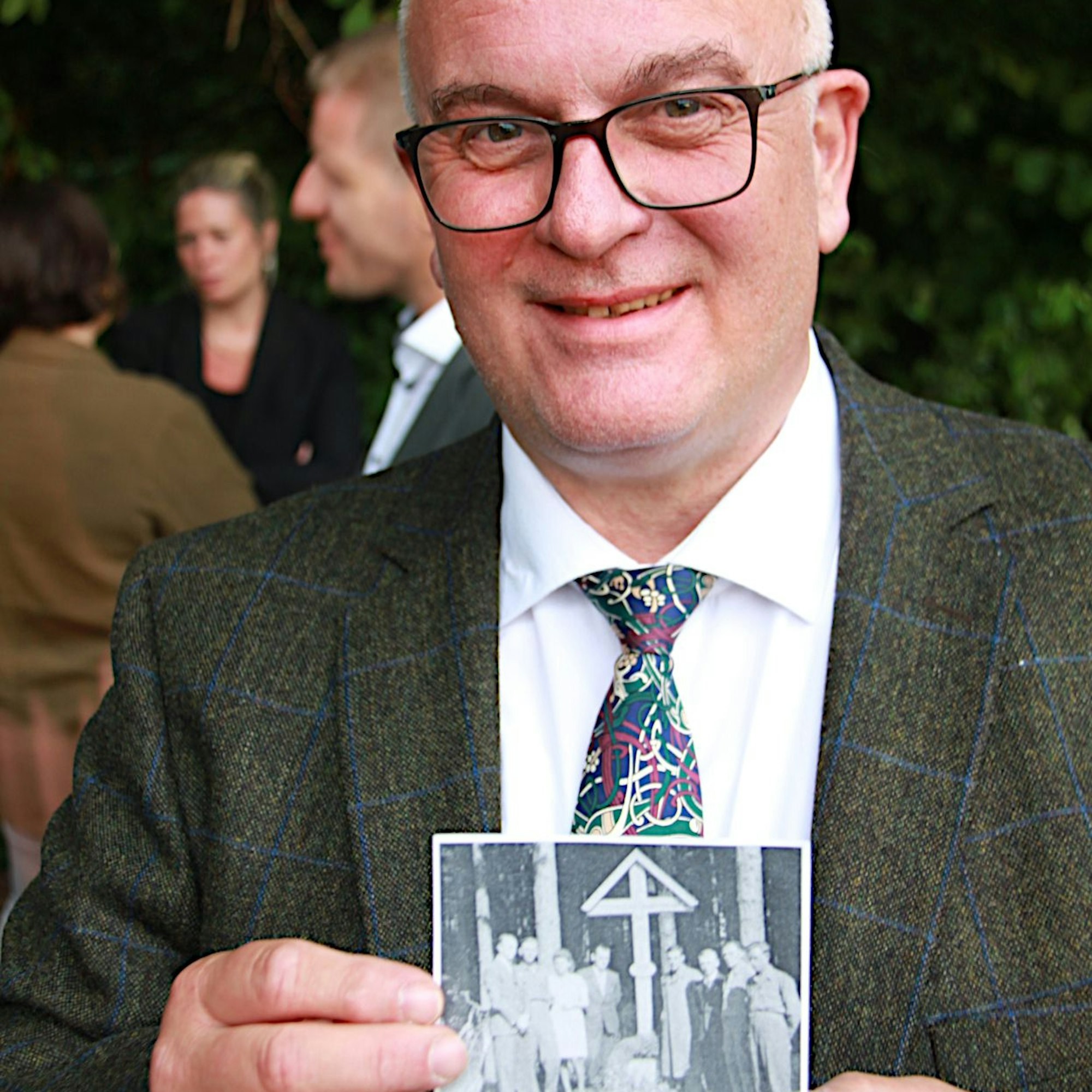 Der Lehrer zeigt ein Foto, das die Errichtung des nach Kriegsende errichteten Kreuzes zeigt.