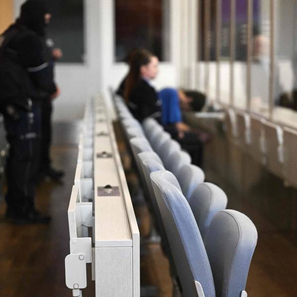 Im Gerichtssaal: Die Anklagebank mit einem Mann und einer Frau im Hintergrund ist zu sehen.
