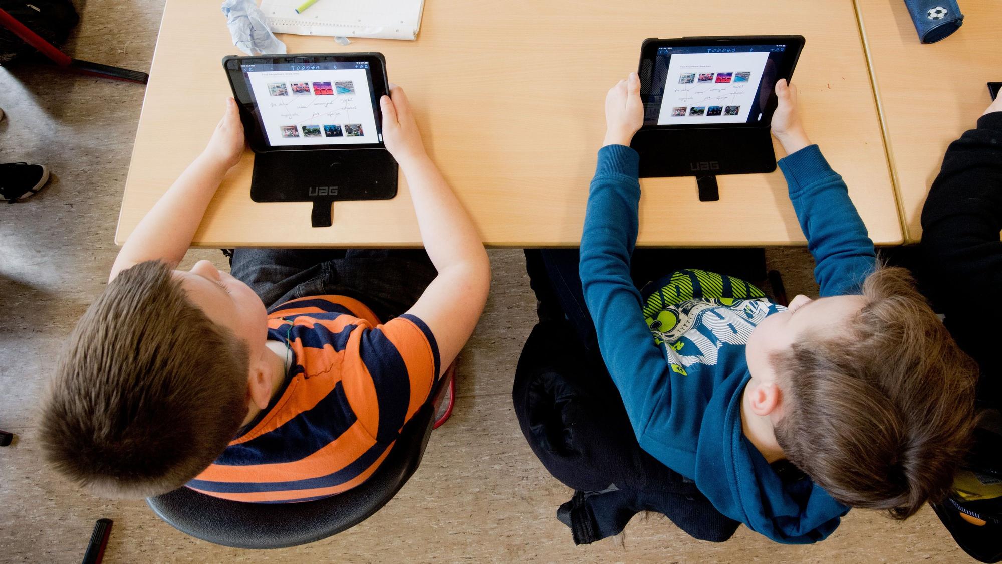 Auf dem Bild sind zwei Schüler mit iPads zu sehen.