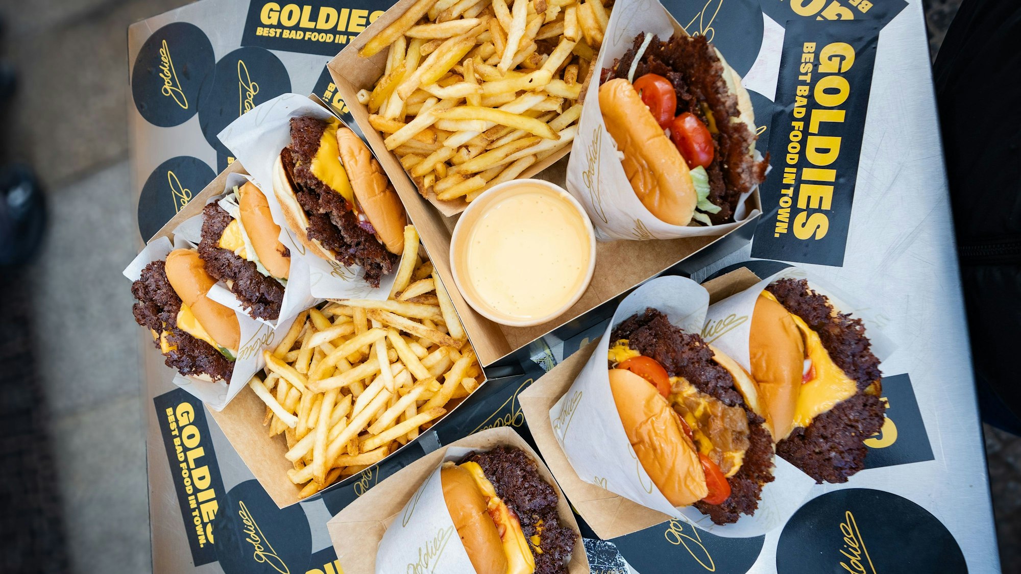 Goldies präsentiert seine Smashburger und Pommes.