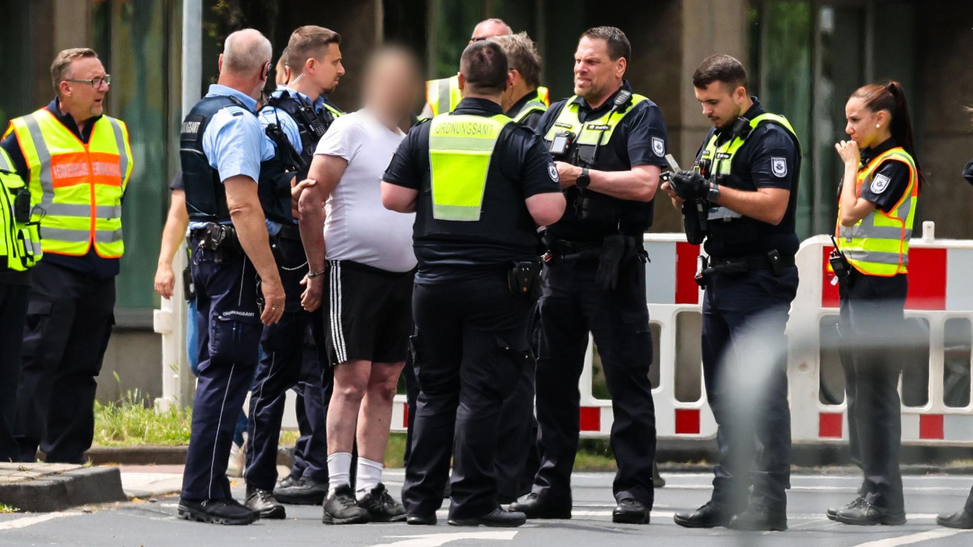 04.06.2025, Nordrhein-Westfalen, Köln: An einer Sperrstelle haben Beamte einen Mann aufgehalten, der zuvor versucht haben soll, mit einem Fahrrad in das Evakuierungsgebiet zu fahren. Am Montag waren im Stadtteil Deutz drei Bomben aus dem Zweiten Weltkrieg entdeckt worden. Foto: Christoph Reichwein/dpa - ACHTUNG: Person(en) wurde(n) aus rechtlichen Gründen gepixelt +++ dpa-Bildfunk +++