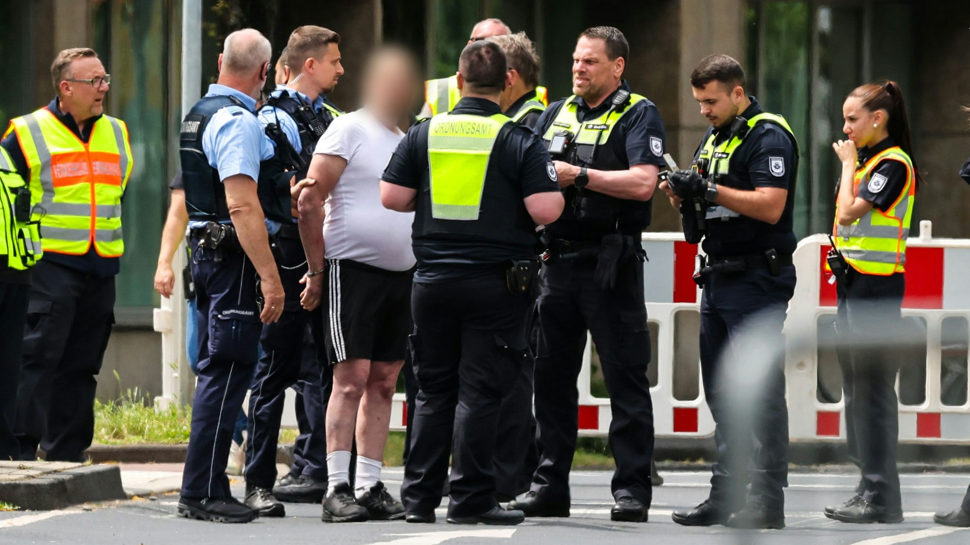 04.06.2025, Nordrhein-Westfalen, Köln: An einer Sperrstelle haben Beamte einen Mann aufgehalten, der zuvor versucht haben soll, mit einem Fahrrad in das Evakuierungsgebiet zu fahren. Am Montag waren im Stadtteil Deutz drei Bomben aus dem Zweiten Weltkrieg entdeckt worden. Foto: Christoph Reichwein/dpa - ACHTUNG: Person(en) wurde(n) aus rechtlichen Gründen gepixelt +++ dpa-Bildfunk +++