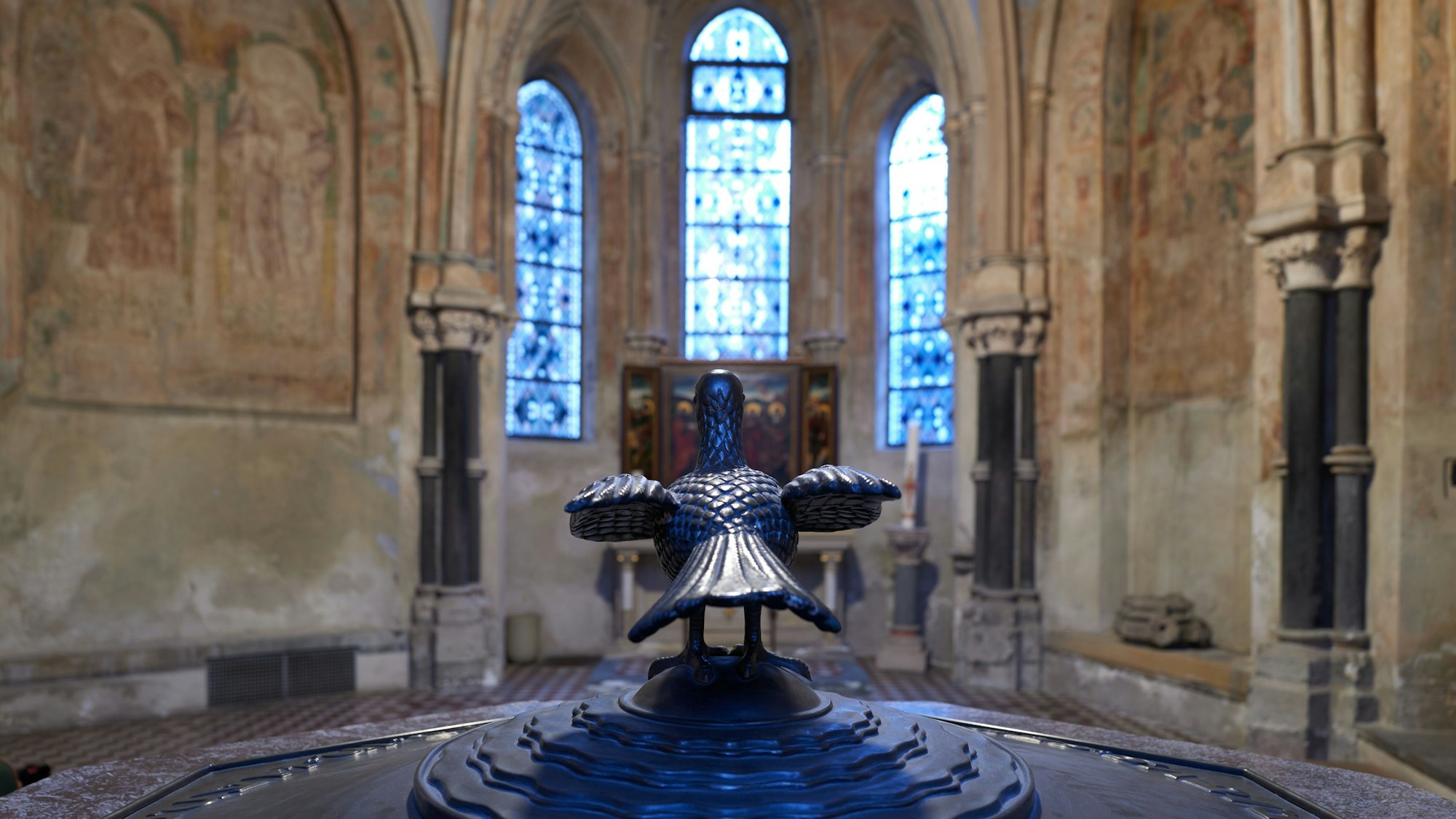 Die Taufkapelle der Kirche Sankt Gereon von innen mit Blick auf das Taufbecken im Vordergrund und dessen Abdeckung mit einer Taube.