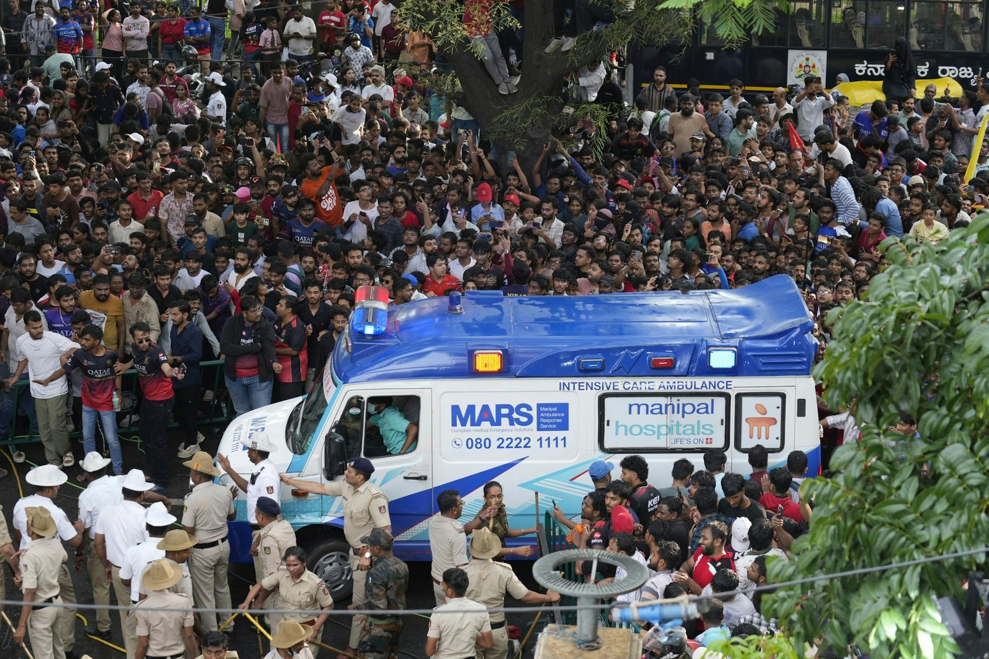 Ein Krankenwagen bahnt sich den Weg durch eine Menschenmenge am M. Chinnaswamy-Stadion in der indischen Stadt Bengaluru.
