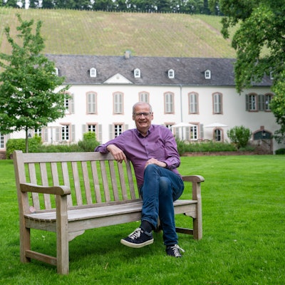 Günther Jauch sitzt auf einer Bank vor seinem Weingut von Othegraven.
