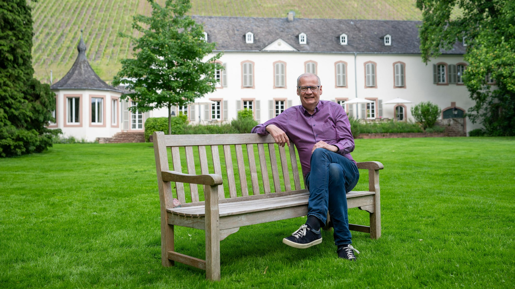 Günther Jauch sitzt auf einer Bank vor seinem Weingut von Othegraven.