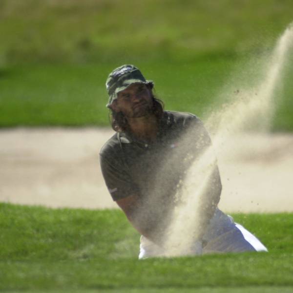 Ein Golfspieler schlägt einen Ball.