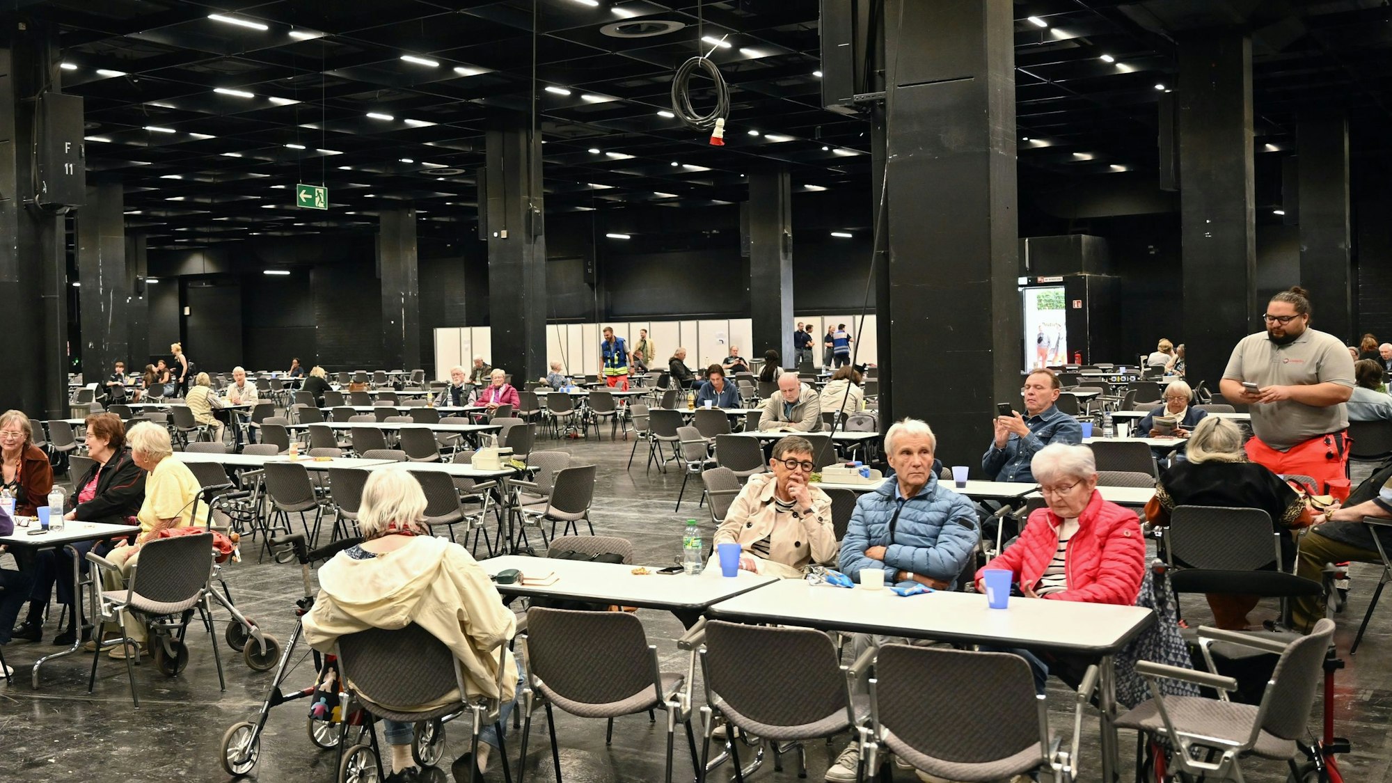 Menschen warten in der Anlaufstelle der Stadt Köln in einer Messehalle auf da Ende der Bombenentschärfung.