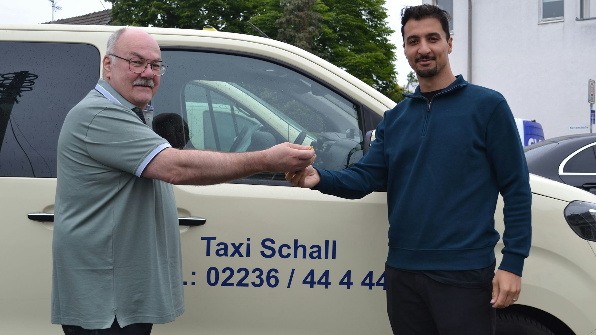 Zu sehen sind Peter Schall und Sirac Kurt vor einem Taxi.