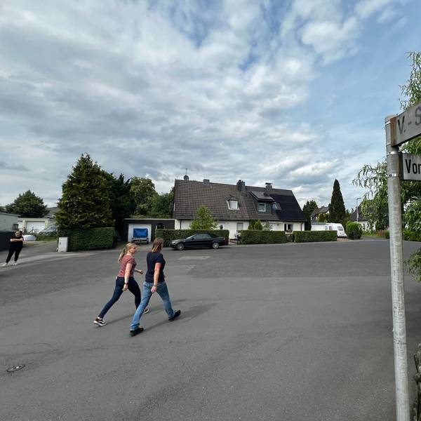 Zwei Passanten gehen über einen Platz.