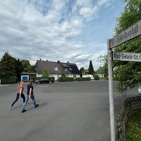 Zwei Passanten gehen über einen Platz.