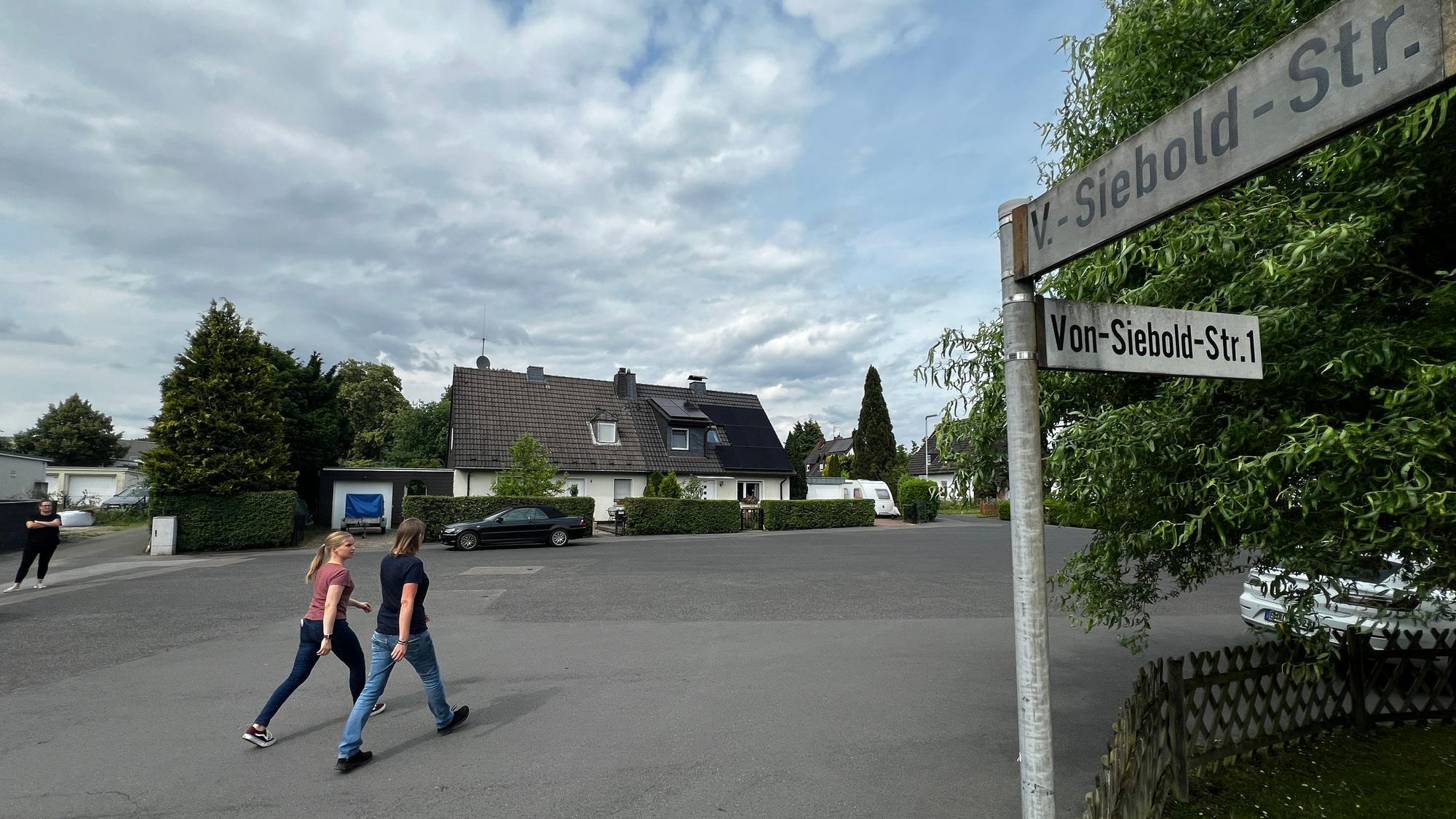 Zwei Passanten gehen über einen Platz.