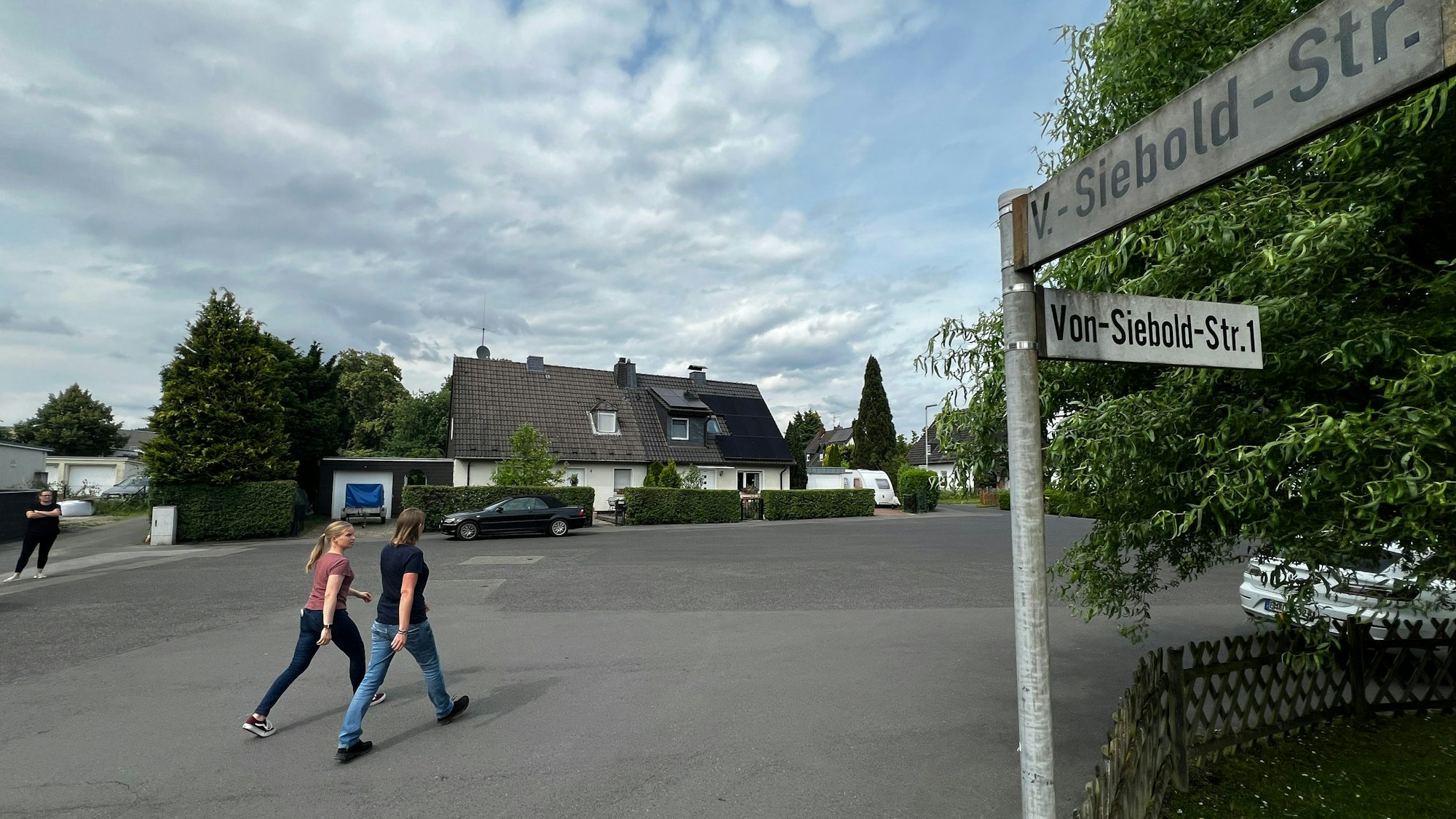 Zwei Passantinnen laufen über einen asphaltierten Platz.