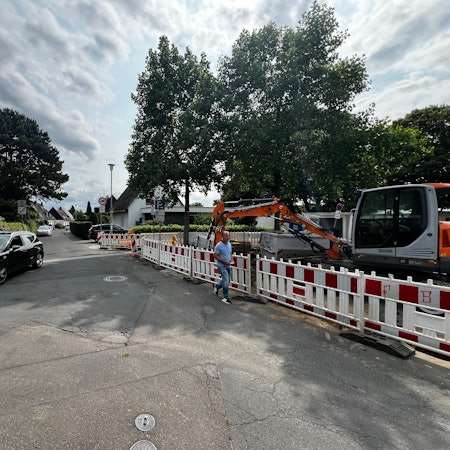 Ein Auto fährt über einen asphaltierten Platz in Opladen an Menschen vorbei.