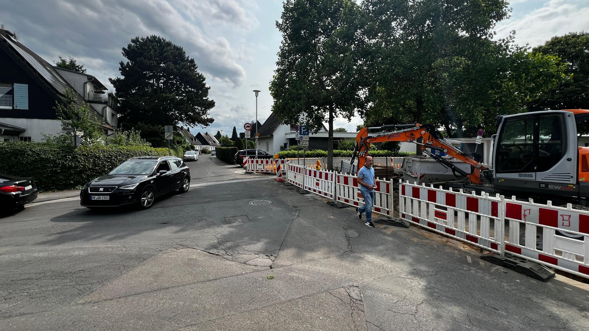 Ein Auto fährt über einen asphaltierten Platz in Opladen an Menschen vorbei.