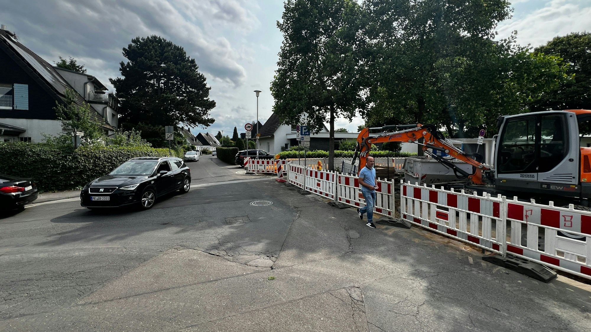 Ein Auto fährt über einen asphaltierten Platz in Opladen an Menschen vorbei.
