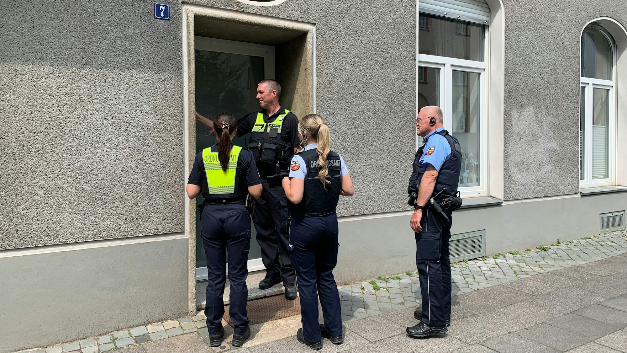 04.06.2025, Nordrhein-Westfalen, Köln: Ein Mitarbeiter vom Ordnungsamtes liest bei einem Klingeldurchgang vor einer einer Bombenentschärfung einen Zettel an einer Haustür. Am Montag waren im Stadtteil Deutz drei Bomben aus dem Zweiten Weltkrieg entdeckt worden Foto: Henning Kaiser/dpa +++ dpa-Bildfunk +++