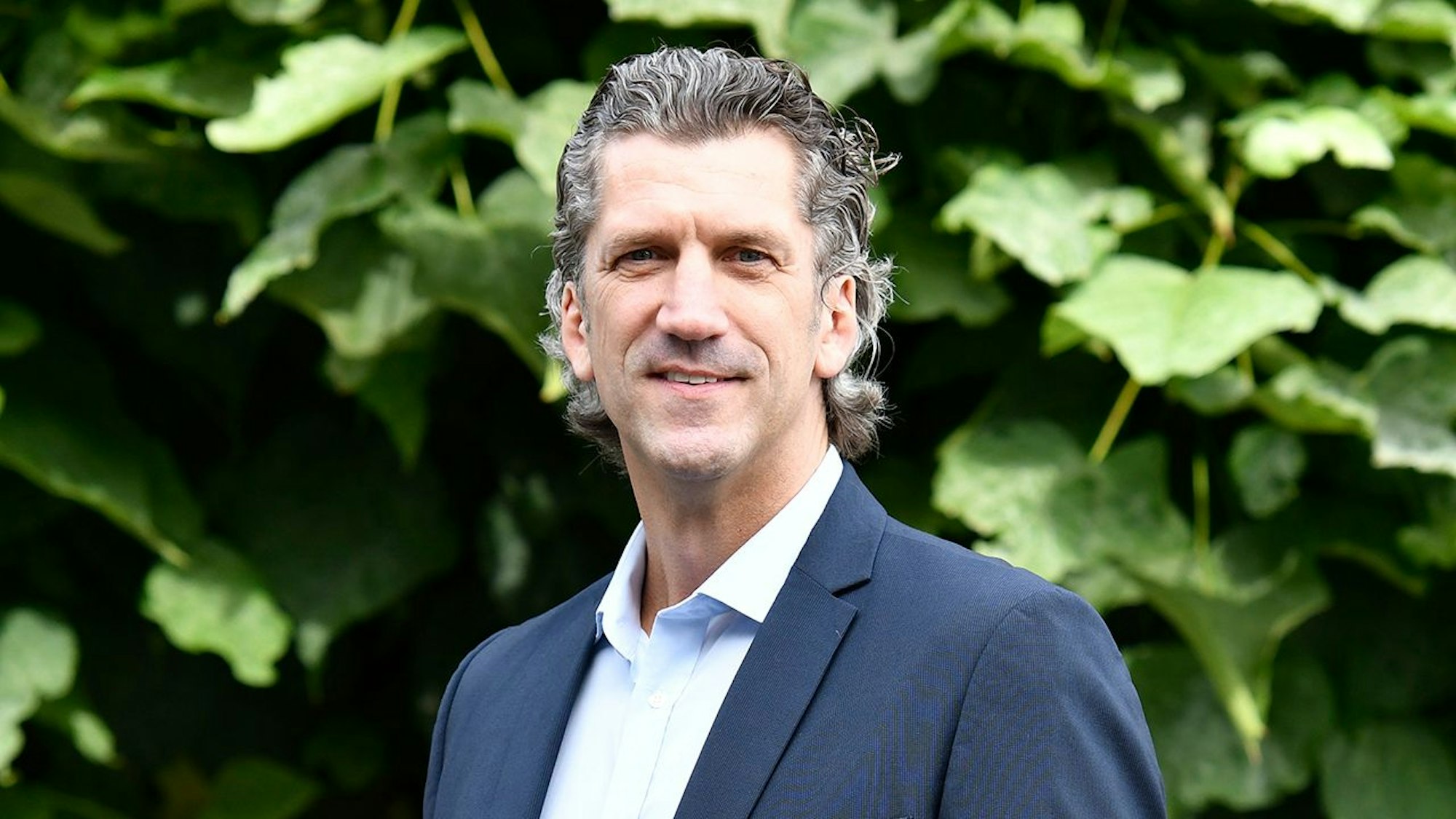 Auf dem Bild ist ein Portrait des Niederlassungsleiter der Deutschen Marktgilde zu sehen, er trägt einen dunklen Anzug und eine Krawatte.