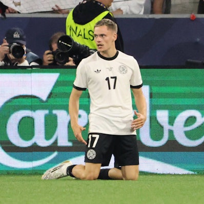 Florian Wirtz kniet auf dem Rasen in München.