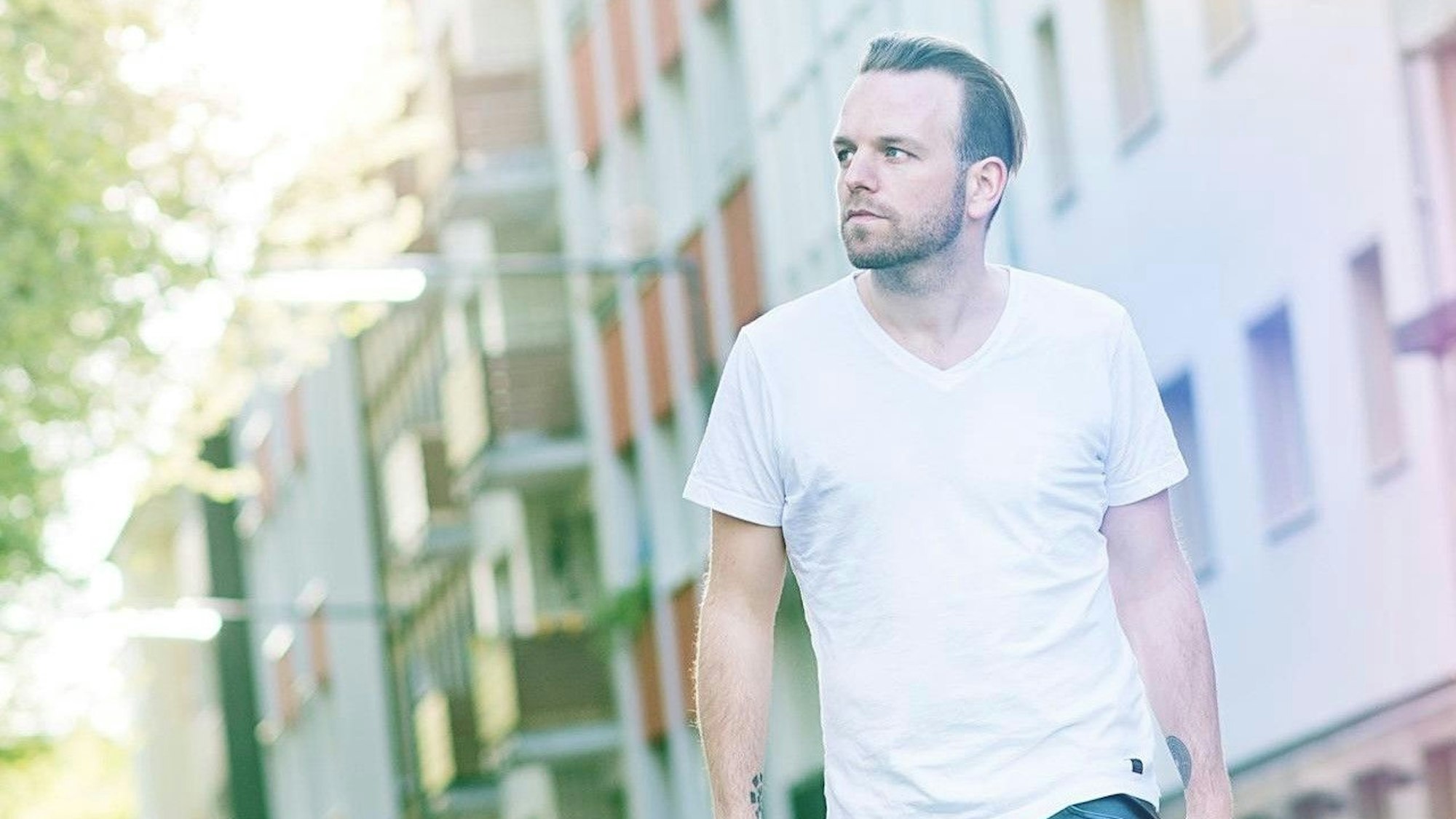 Henning Neuser auf einem Profi-Bild: Er läuft im T-Shirt mit versonnenem Blick durch eine Straße im Morgenlicht.