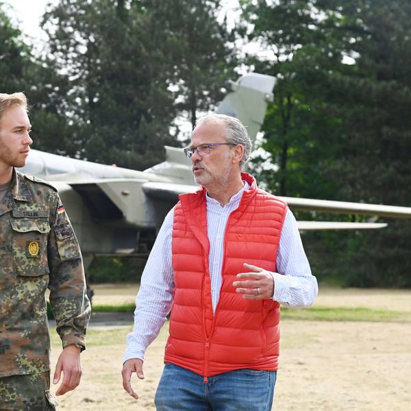 Die beiden Männer sind im Gespräch unterwegs auf dem Kasernengelände. Der junge trägt Uniform in Tarnfarbe.