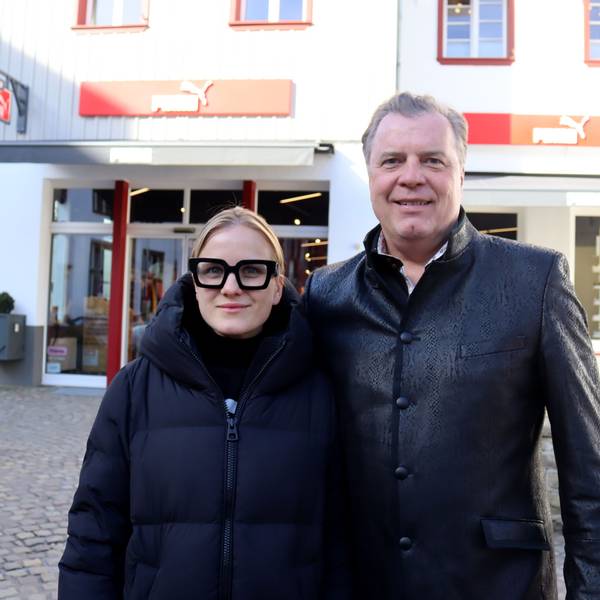 Julia und Marc Brucherseifer stehen vor dem Puma Store, darüber befindet sich die Zentrale des City Outlets.