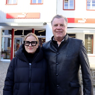 Julia und Marc Brucherseifer stehen vor dem Puma Store, darüber befindet sich die Zentrale des City Outlets.
