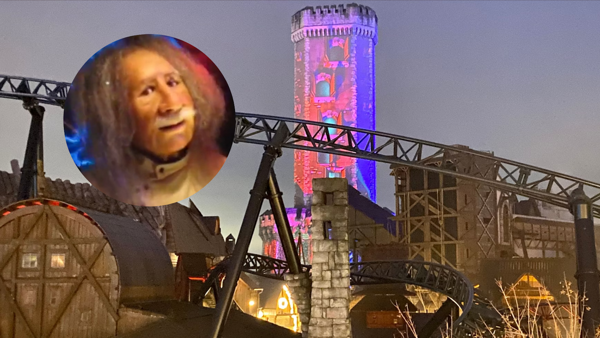 Ein geheimnisvoller Turm ragt über das Phantasialand, im Vordergrund sieht man eine Achterbahn in der Dämmerung.