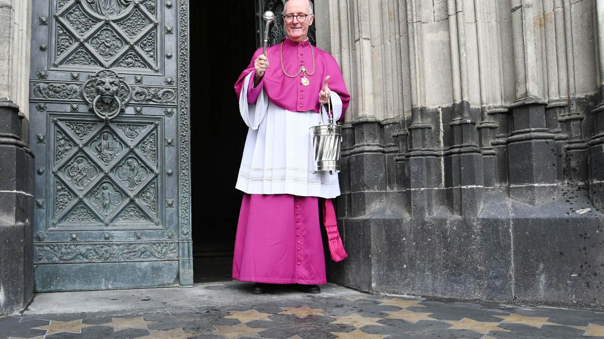 Zu sehen ist Monsignore Guido Assmann vor dem Kölner Dom.