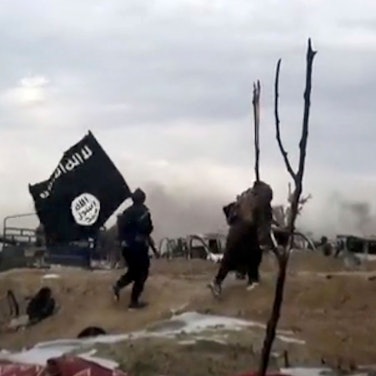 ARCHIV - 19.03.2019, Syrien, Baghus: IS-Kämpfer laufen mit einer IS-Flagge. (Screenshot aus einem Video der Amaq News Agency, dem Medienarm des Islamischen Staates - Beste verfügbare Qualität; Illustration zu "14-jähriger Kölner unter Terrorverdacht") Foto: Amaq News Agency/AP/dpa +++ dpa-Bildfunk +++