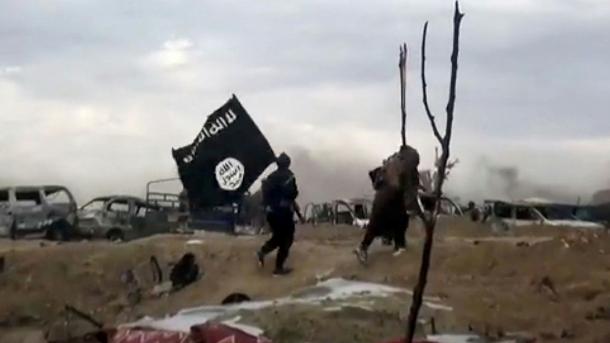 ARCHIV - 19.03.2019, Syrien, Baghus: IS-Kämpfer laufen mit einer IS-Flagge. (Screenshot aus einem Video der Amaq News Agency, dem Medienarm des Islamischen Staates - Beste verfügbare Qualität; Illustration zu "14-jähriger Kölner unter Terrorverdacht") Foto: Amaq News Agency/AP/dpa +++ dpa-Bildfunk +++