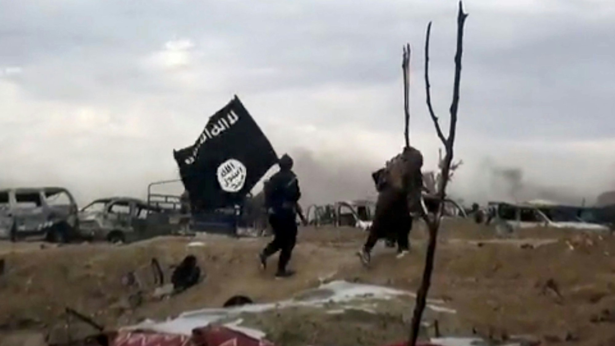 ARCHIV - 19.03.2019, Syrien, Baghus: IS-Kämpfer laufen mit einer IS-Flagge. (Screenshot aus einem Video der Amaq News Agency, dem Medienarm des Islamischen Staates - Beste verfügbare Qualität; Illustration zu "14-jähriger Kölner unter Terrorverdacht") Foto: Amaq News Agency/AP/dpa +++ dpa-Bildfunk +++