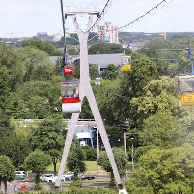 Zu sehen sind Seilbahnen über Kölner Grünflächen.