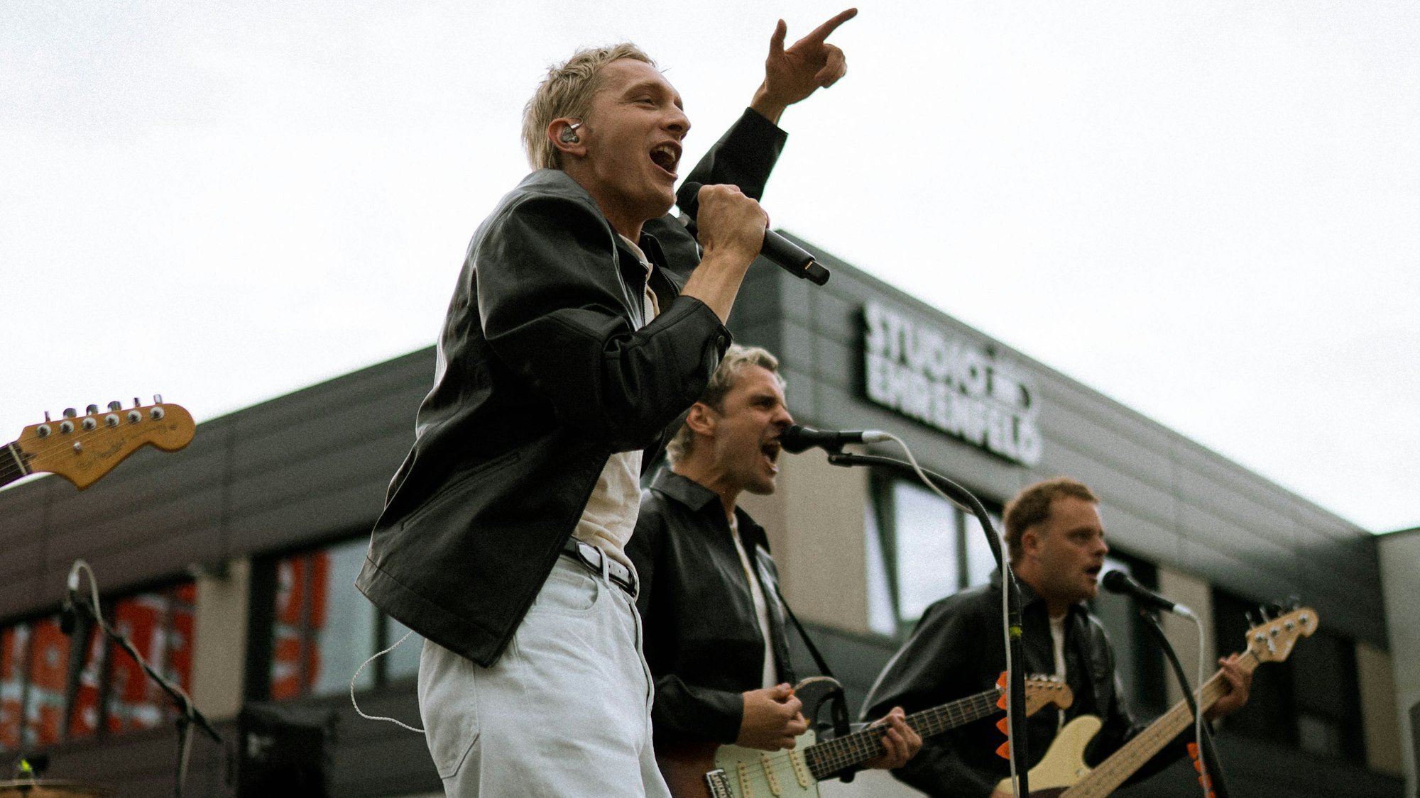 Zu sehen ist die Band Kraftklub in der Seitenansicht auf der Bühne.