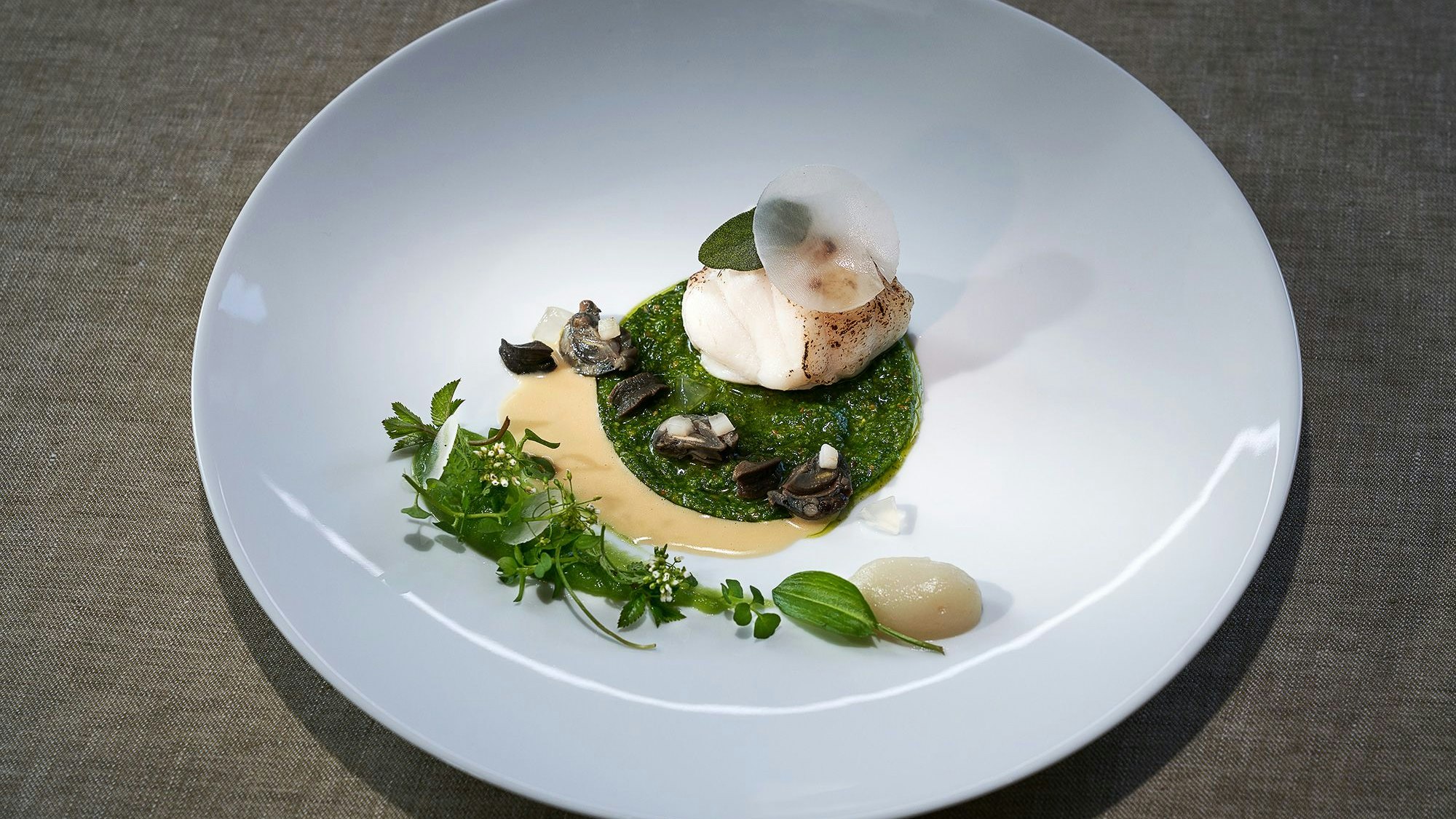 Ein edles Tellergericht ist zu sehen mit vielen Komponenten und aufwändiger Komposition.