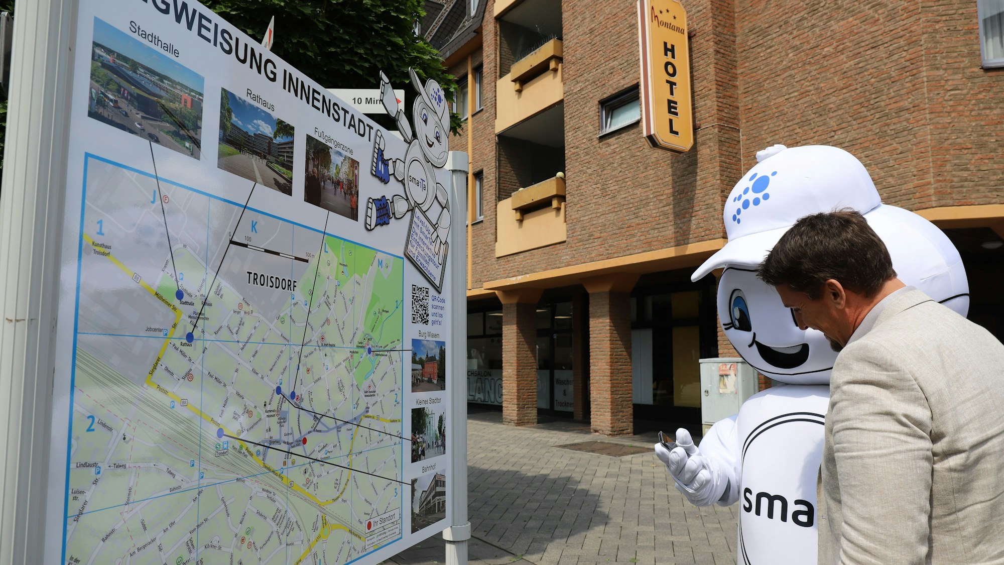 Smart City-Maskottchen SmarTa erklärt Bürgermeister Alexander Biber die App für die Entdeckungstouren.
