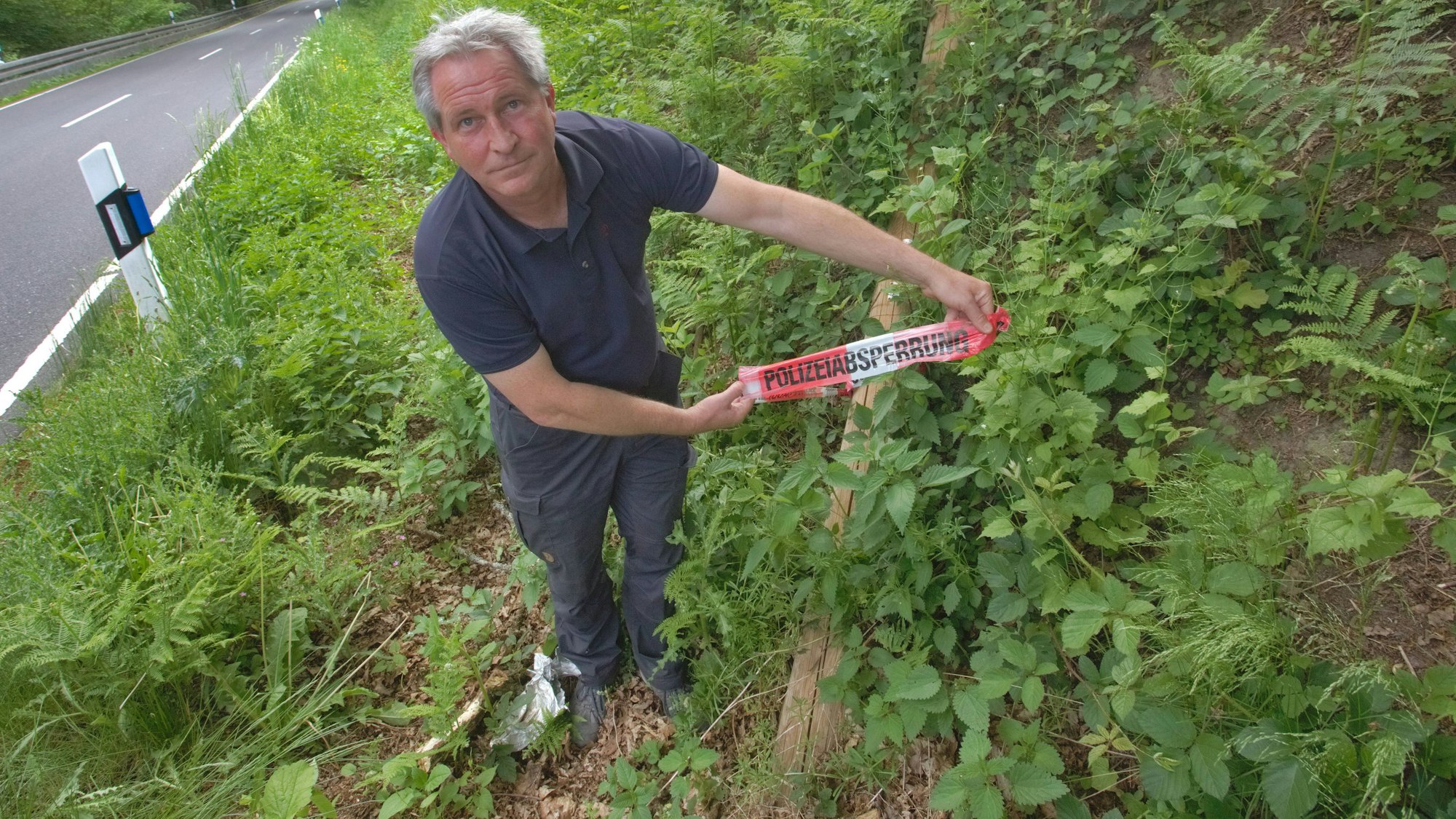 In einem Graben bei Waldbröl-Spurkenbach hat Wastl Roth-Seefrid einen gefällten Leitungsmast entdeckt, daran hängt ein Flatterband von der Polizei.