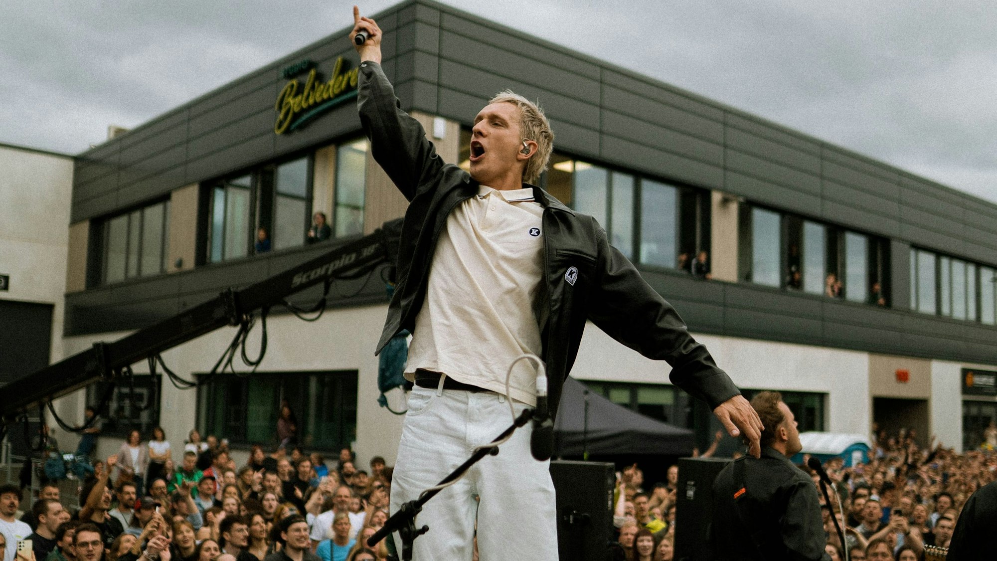 Zu sehen ist Felix Kummer, Leadsänger von Kraftklub, auf der Bühne. Hinter ihm sind Zuschauerinnen und Zuschauer.