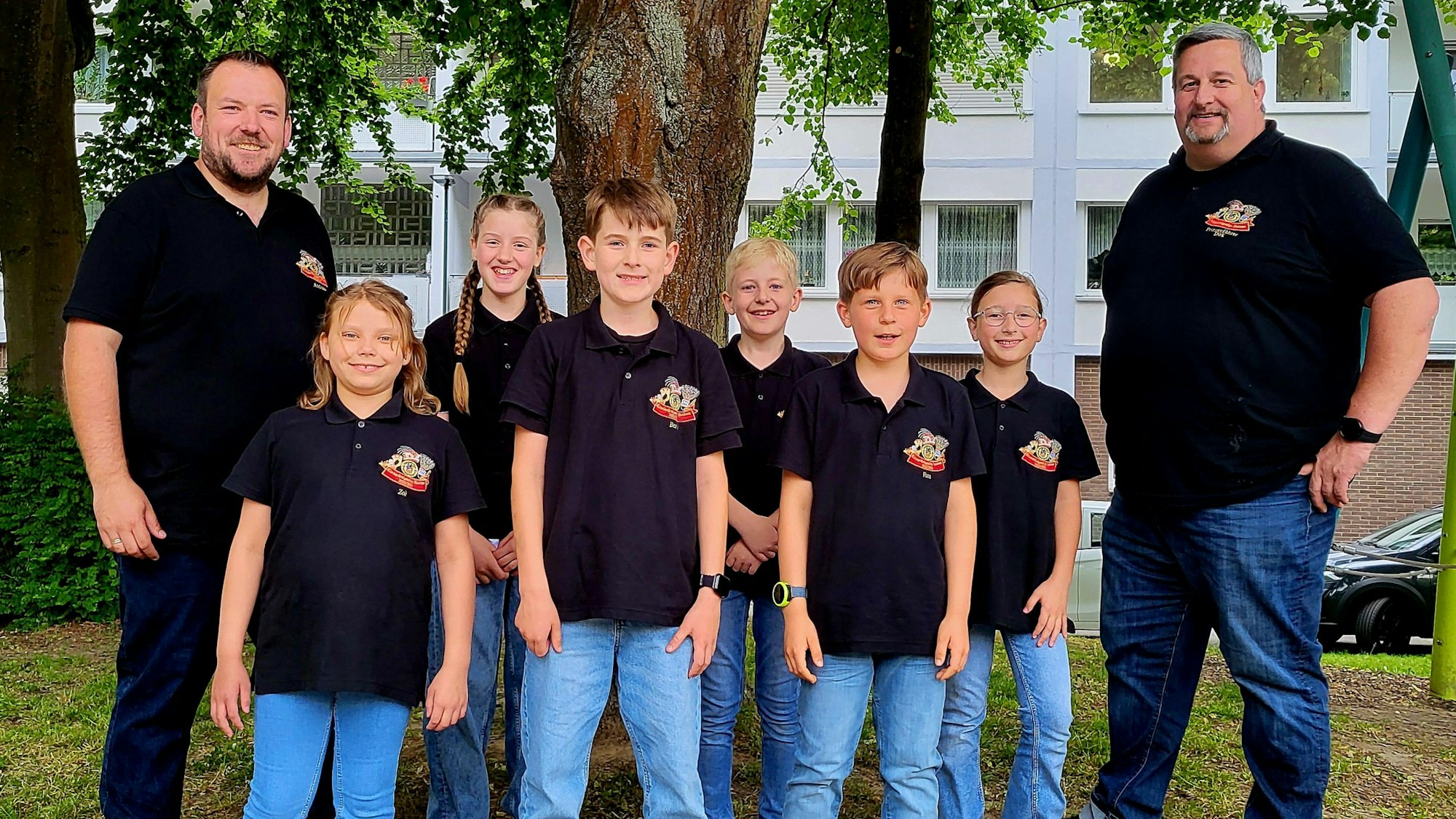 Sechs Kinder und zwei Männer lächeln in die Kamera.