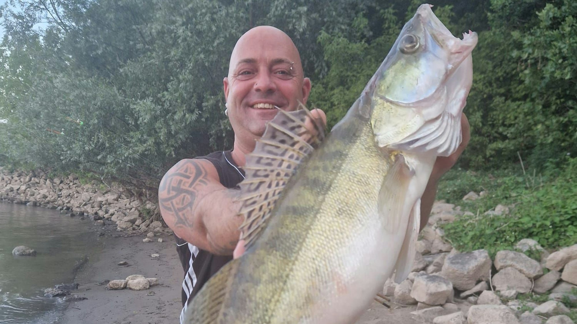 Ein Mann hält einen großen Fisch vor seinen Körper.