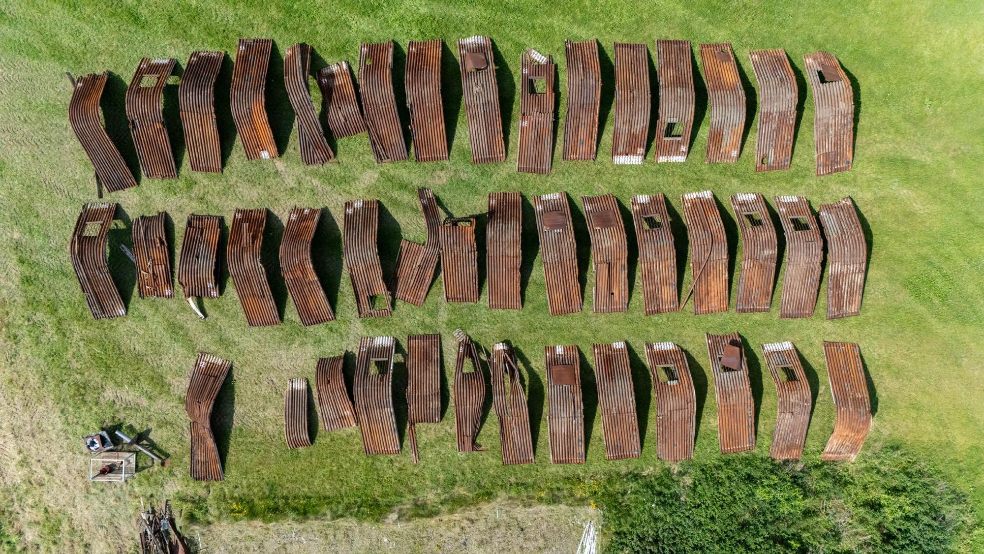Die großen rostigen Blechteile sind sortiert, viele müssen repariert werden, bevor sie wieder zusammengebaut werden können.
