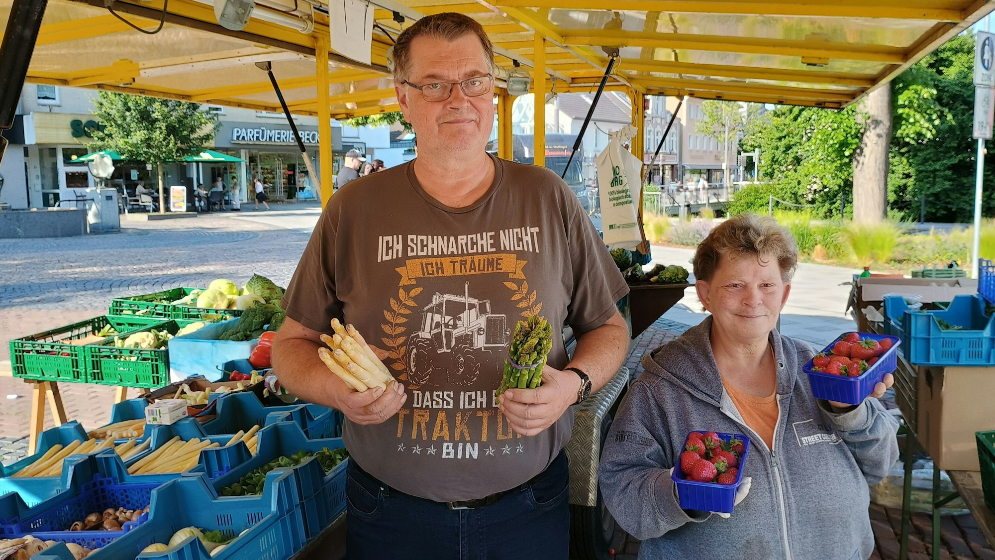 Gerd Hass hält auf dem Bild Spargel in der Hand, Carmen Odenthal zwei Schalen mit Erdbeeren.