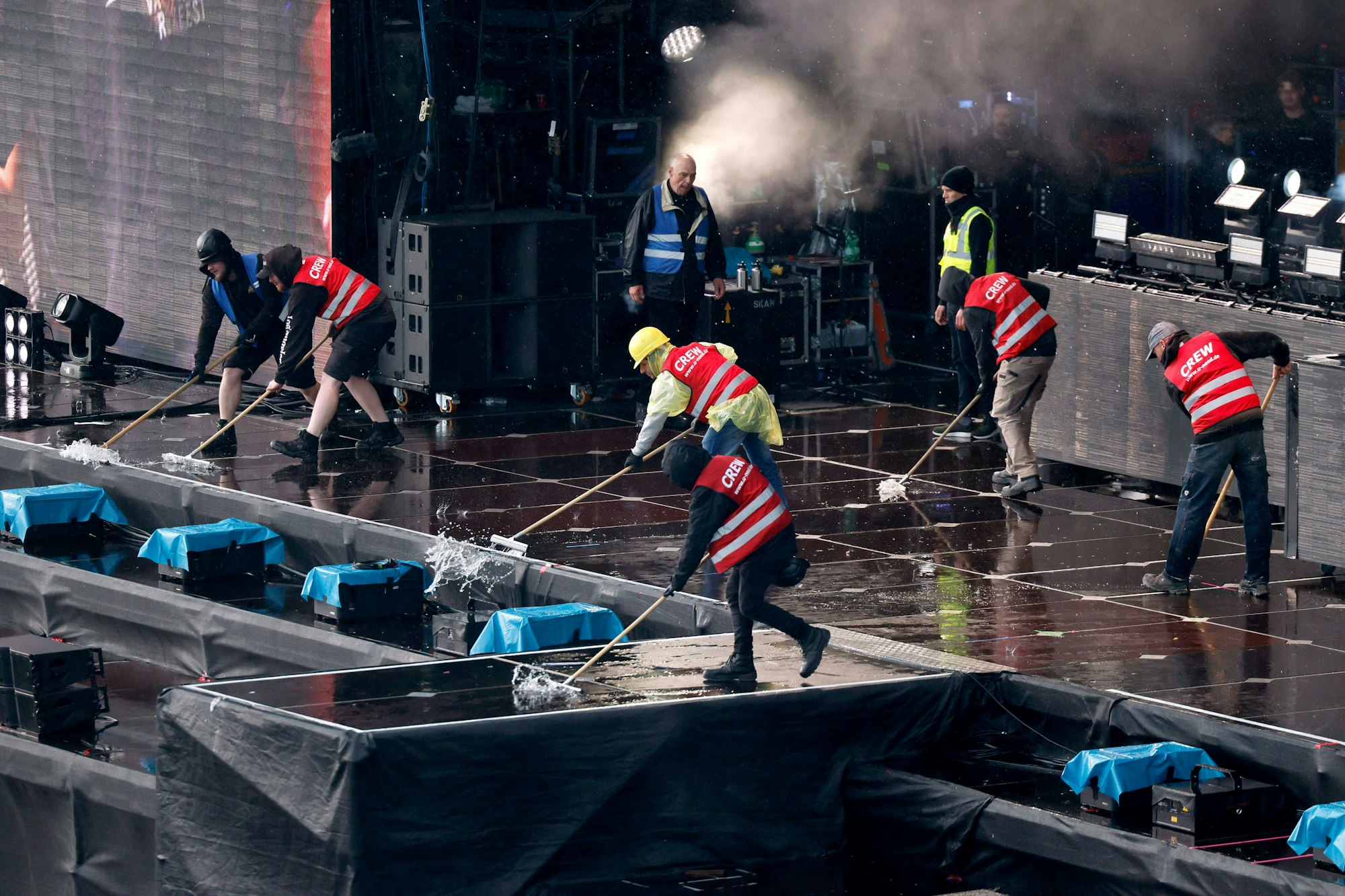 Crew-Mitglieder kehren Regenwasser von der Utopia Stage.
